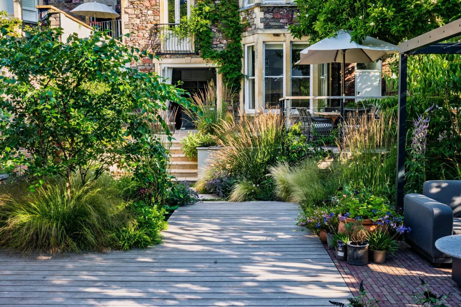 Looking from the finished garden back to the house, with trees, naturalistic planting, and decking