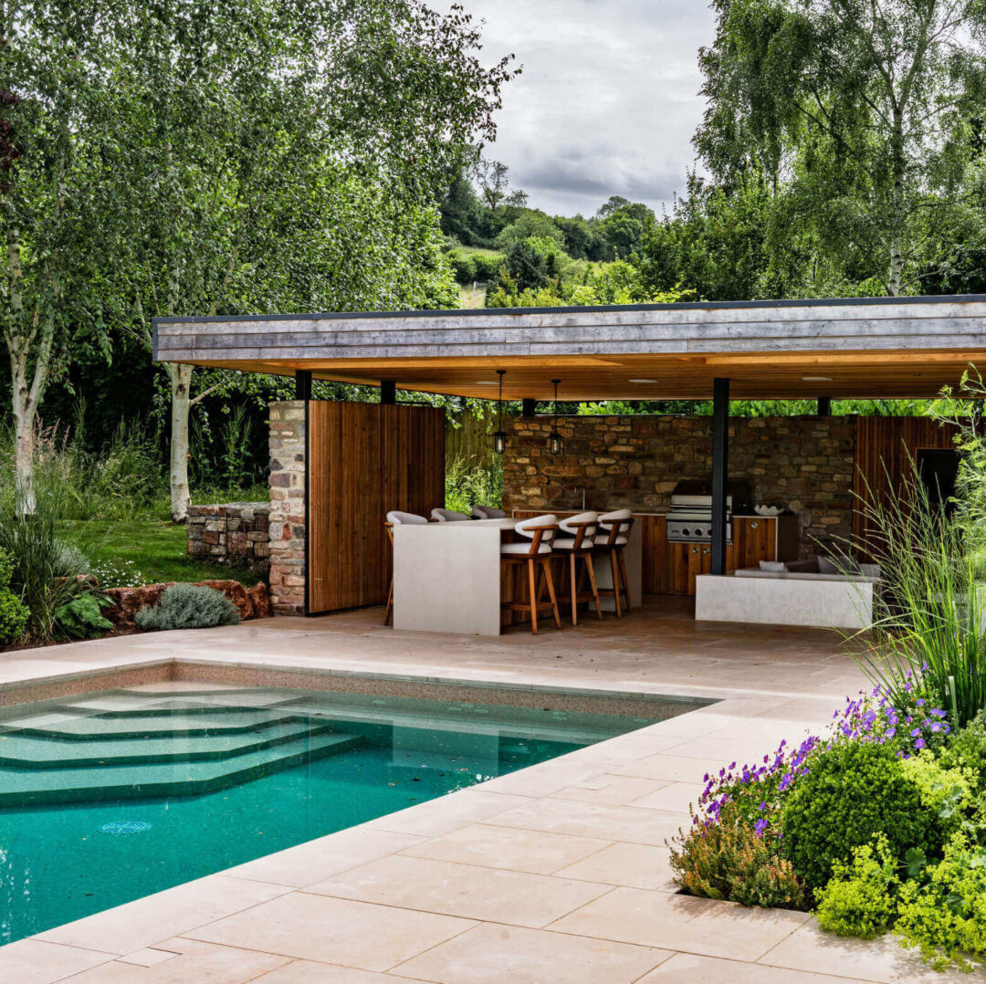 Looking towards the swimming pool and pool house beyond, with naturalistic planting in the fore