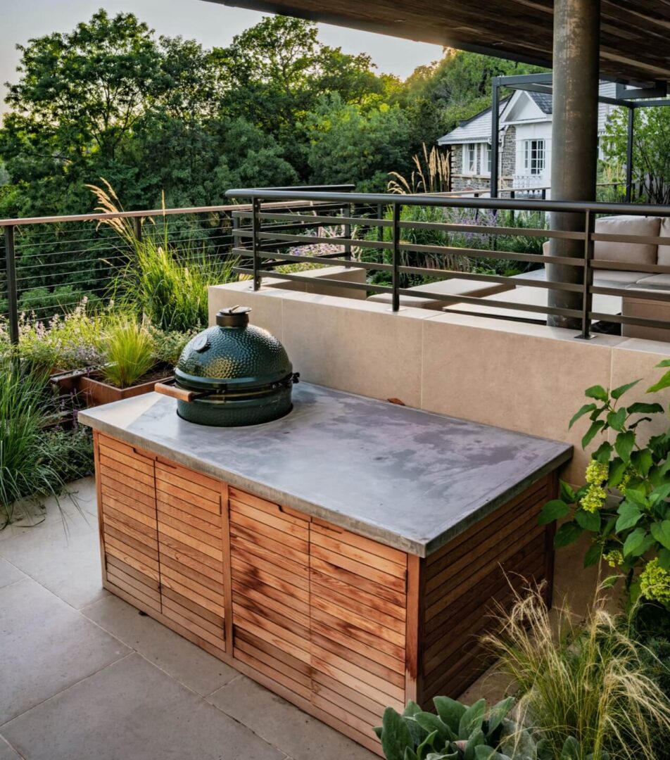 Angle of a terraced garden showing multiple levels, and bespoke cedar and concrete outdoor kitchen with a Big Green Egg