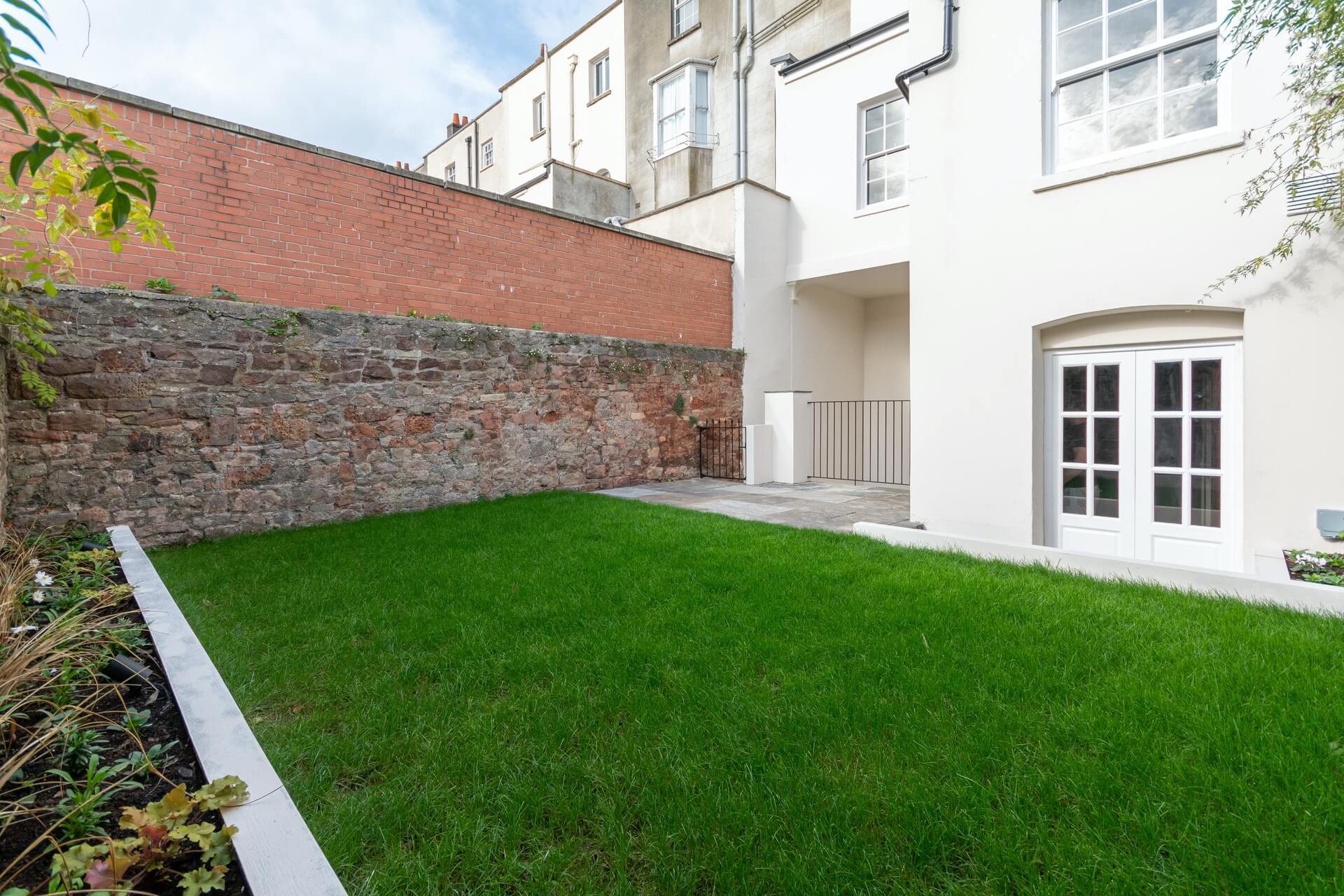 Courtyard garden with large lawn, small planting area on the left, and house on the right